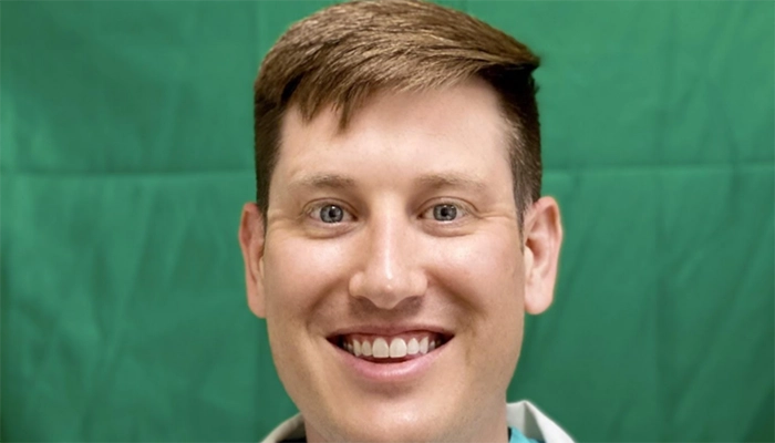 A smiling person against a green background, exuding a friendly and approachable demeanor. The focus is on their expressive eyes and warm smile.