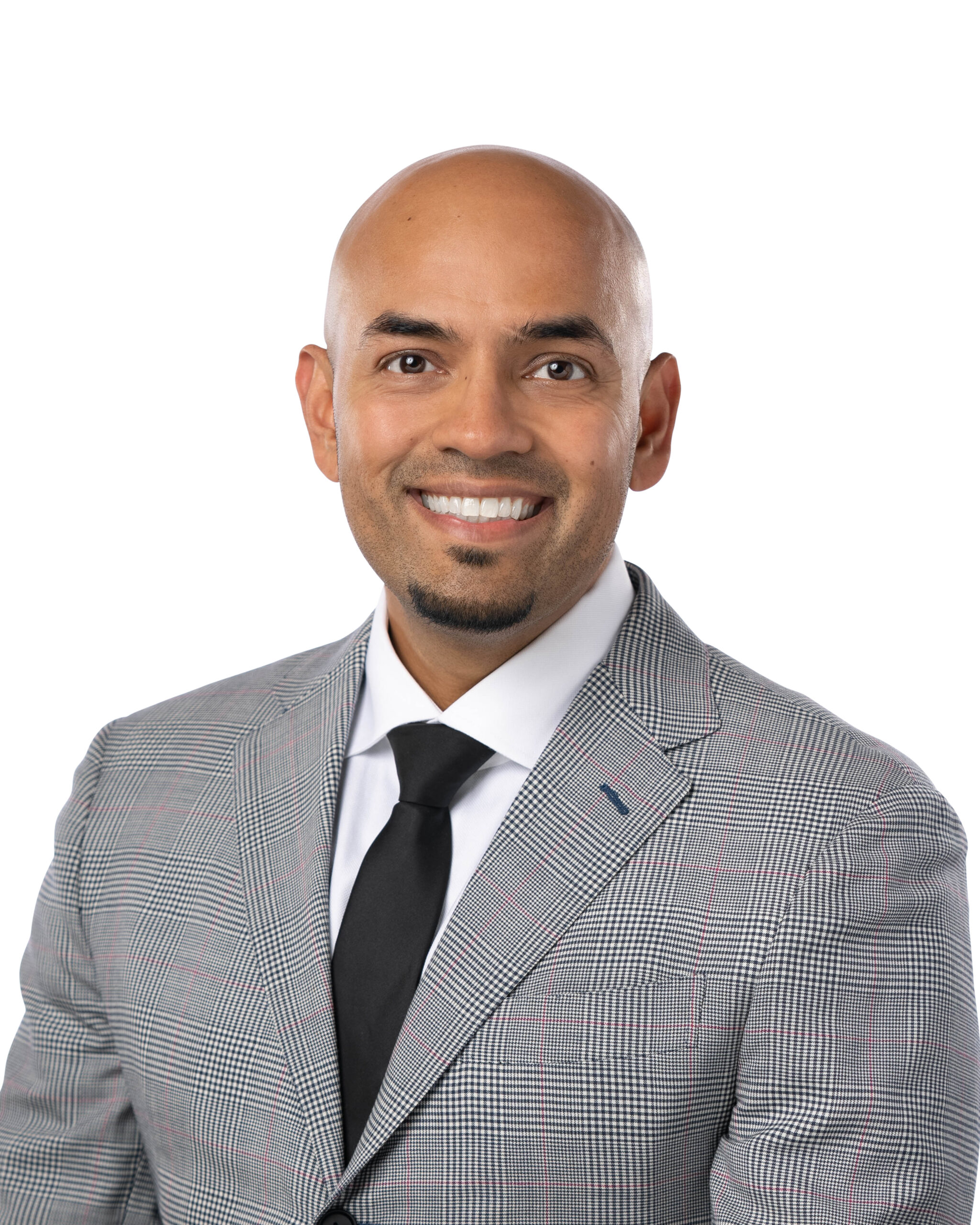 A professional headshot of a smiling woman with shoulder-length blonde hair. She is wearing a bold red leather jacket over a black top and long pearl drop earrings, set against a plain white background.