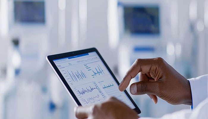Person reviews healthcare project plan on tablet in hospital. Hands inspect project milestones, timeline. Focus on quality improvement, resource allocation. Medical pro analyzes project data
