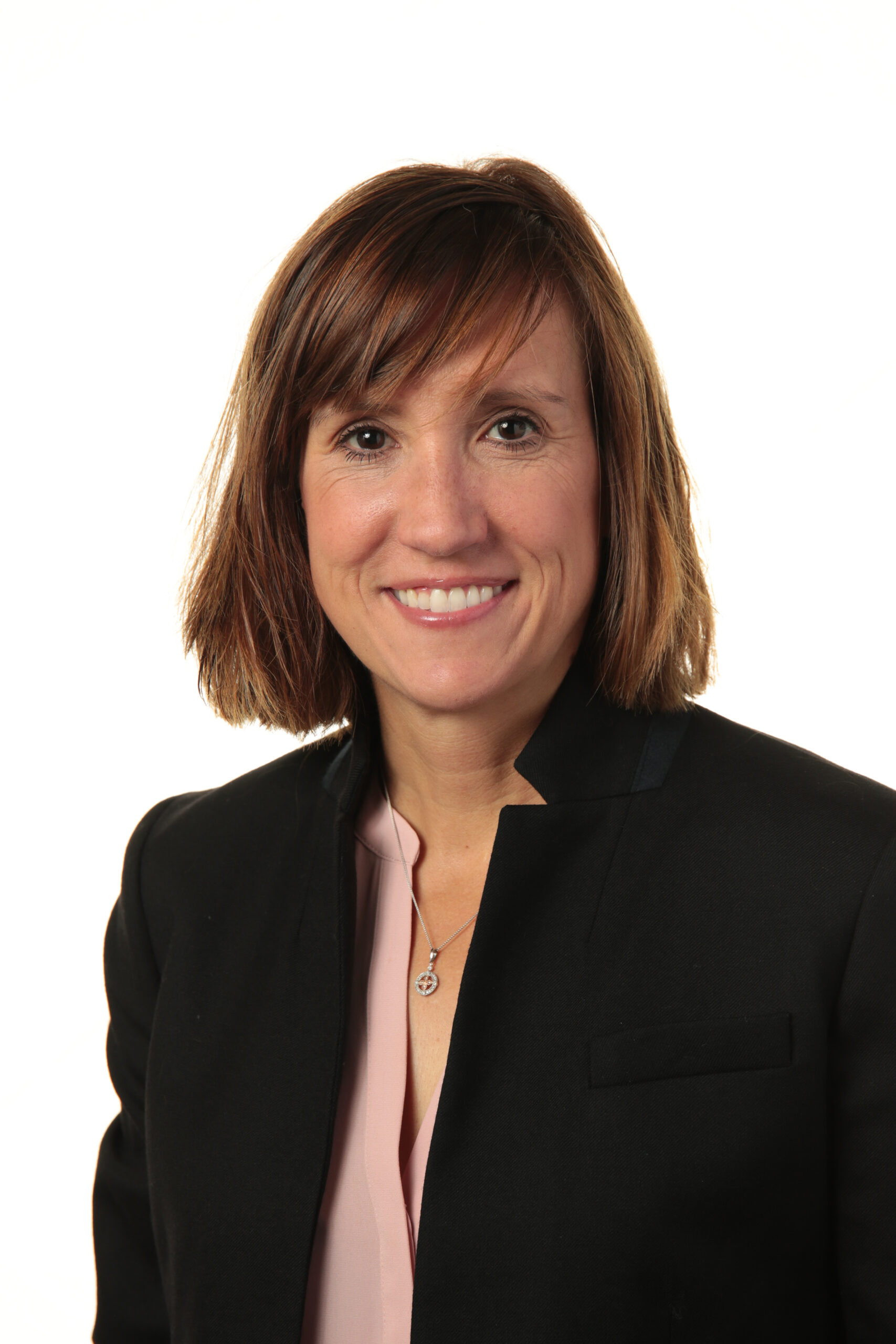 Smiling female doctor with curly hair uses a tablet in a bright medical office. Two blurred colleagues in the background, creating a professional atmosphere.