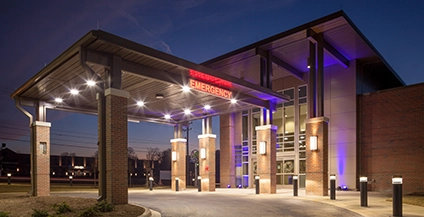 Modern hospital emergency entrance at night with illuminated 