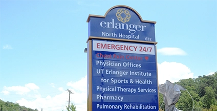 Sign for Erlanger North Hospital against a blue sky. It features emergency services, physician offices, pharmacy, and rehabilitation services.