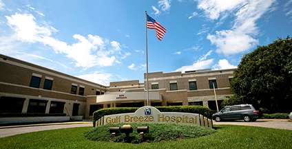 american flag with a sign underneath that says gulf breeze hospital