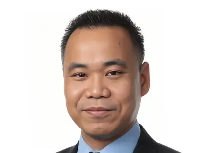 Headshot of William Lee, smiling, wearing a black blazer and a blue button-down shirt.