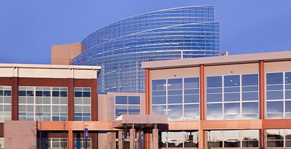 Modern building with curved glass facade and red pillars under a clear blue sky, reflecting a professional and contemporary architectural style.