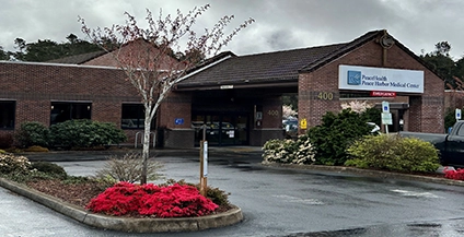 Front entrance of PeaceHealth Peace Harbor Medical Center with brick exterior, covered patient drop-off, and hospital signage.